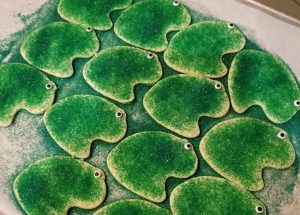 Frog-shaped sugar cookies, topped with green-colored sugar, with googly eyes. These are based on Catapult Greater Pittsburgh's Logo